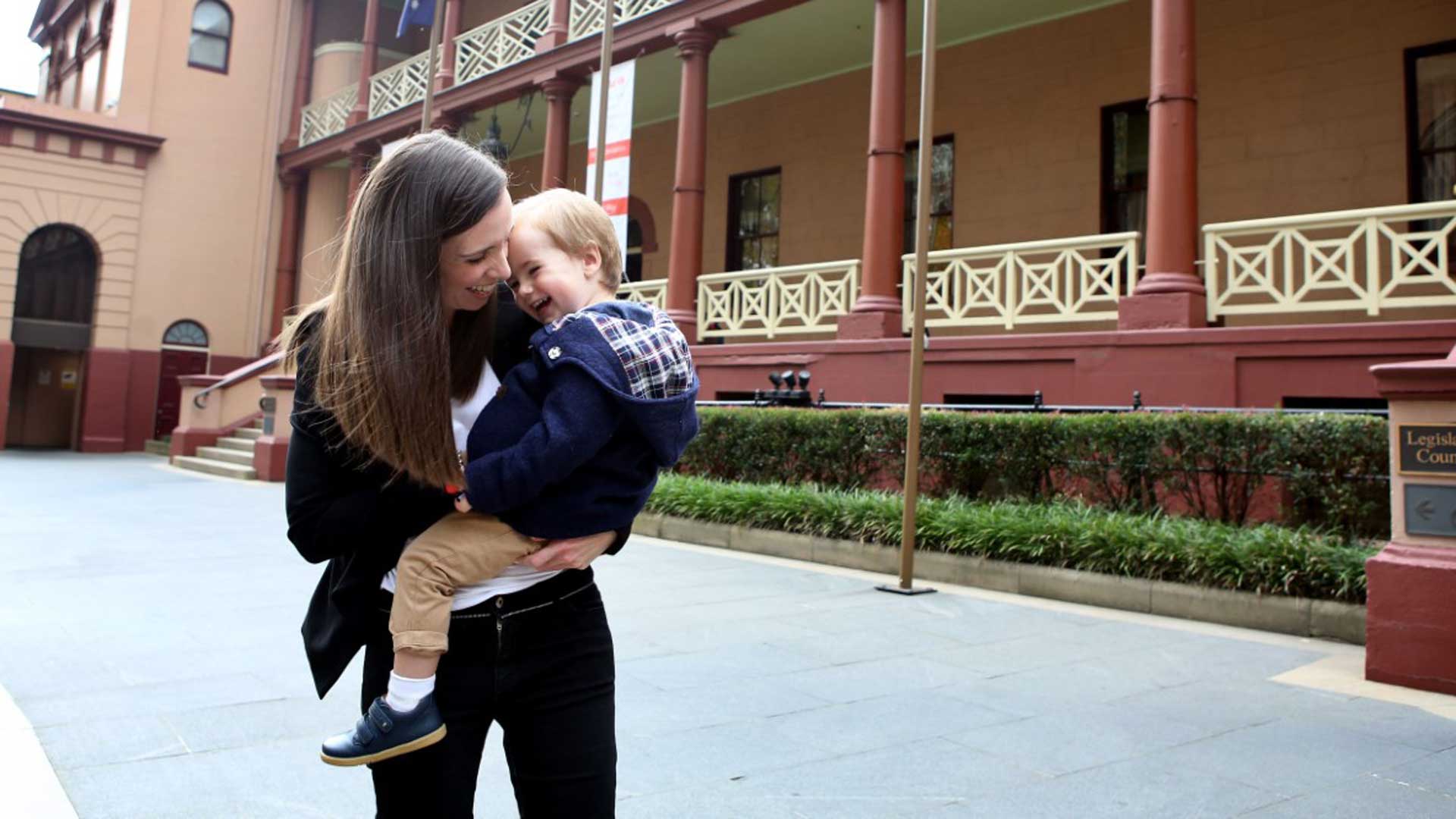 Woman cuddling child outside the NSW Parliament