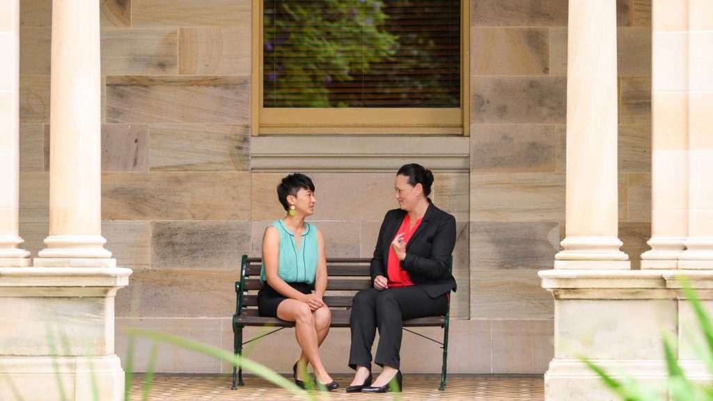 Two women on a bench in a historical environment - QUT alums