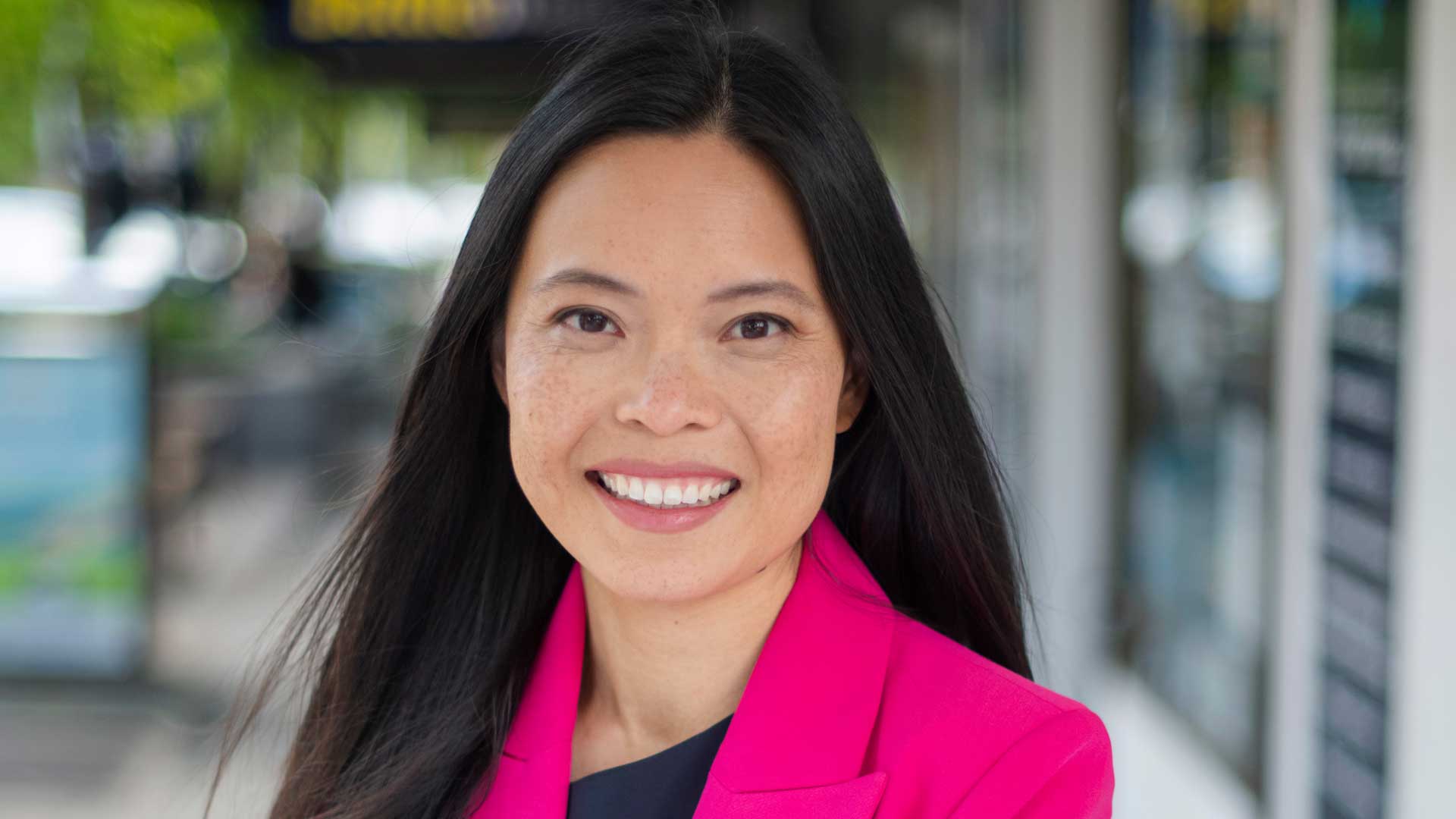 Photograph of Sally Sitou: smiling asian woman wearing a bright pink blazer