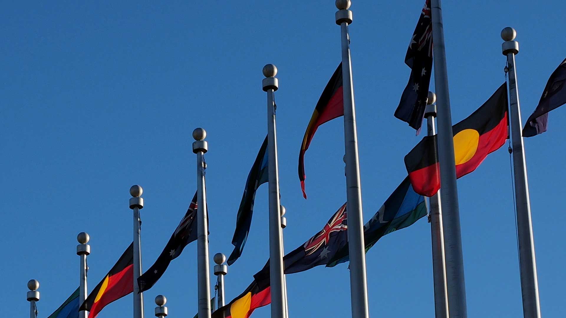 Aboriginal and Australian flags flying across a blue sky