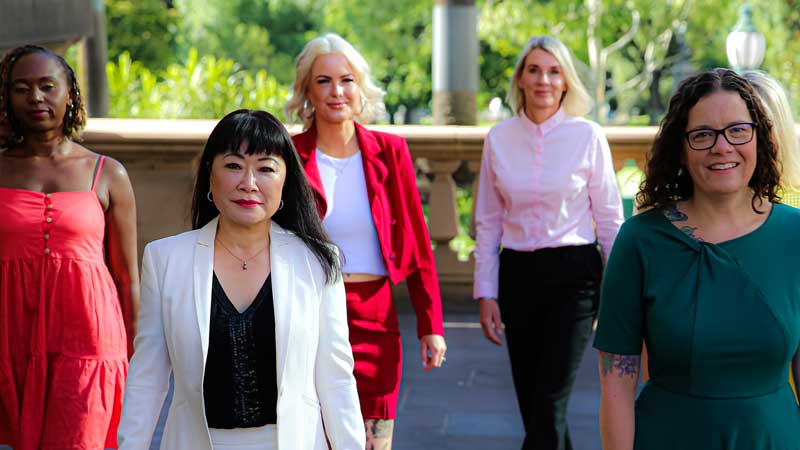 Five brightly dressed professional women walking towards camera: Pathways to Politics alums