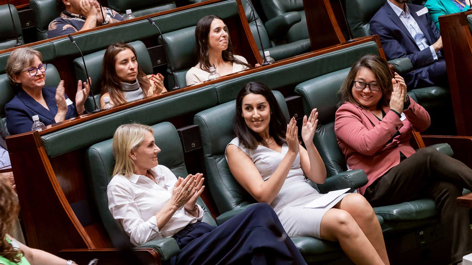 Photo of diverse group of women applauding in Victorian parliament chambers