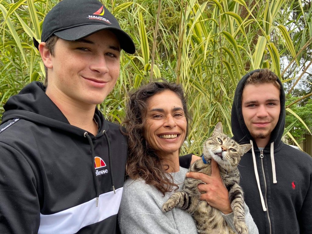 Moo D'Ath with her cat and two smiling teenage sons