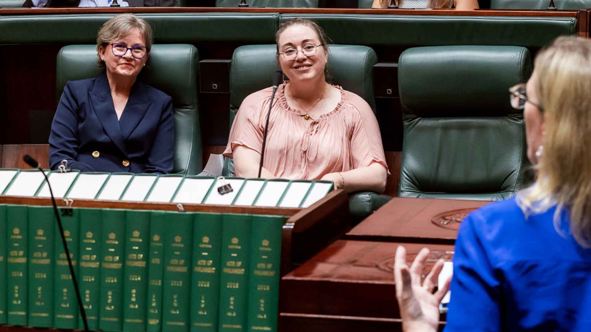 Two Pathways to Politics alums, smiling, watching an address in the Victorian Parliament chambers