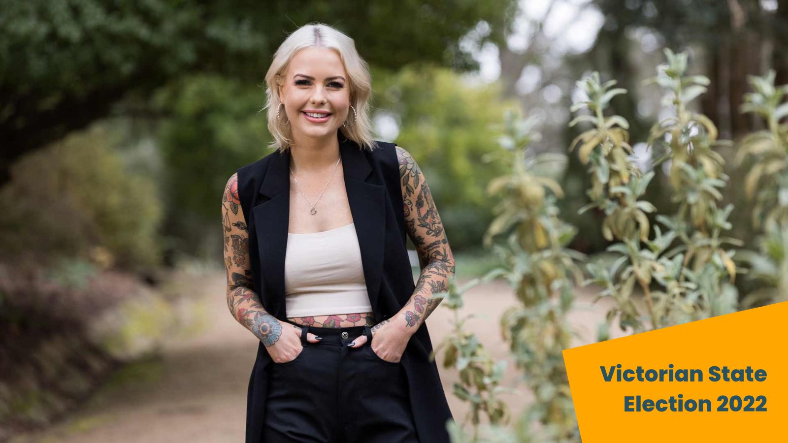 Photo of Georgie Purcell smiling, sowing off tattoos on her arms. Overlaid text reads, "Victorian State election 2022"