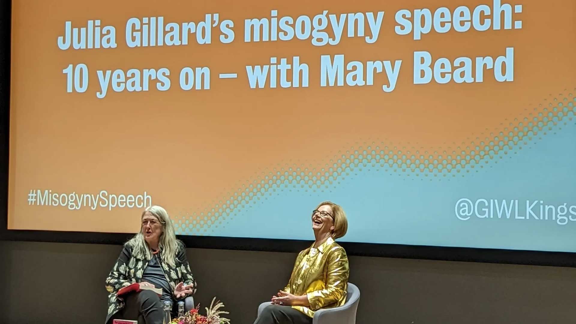 Julia Gillard and Mary Beard on stage, screen behind says "Julia Gillard's misogyns speech ten years on - with Mary Beard"