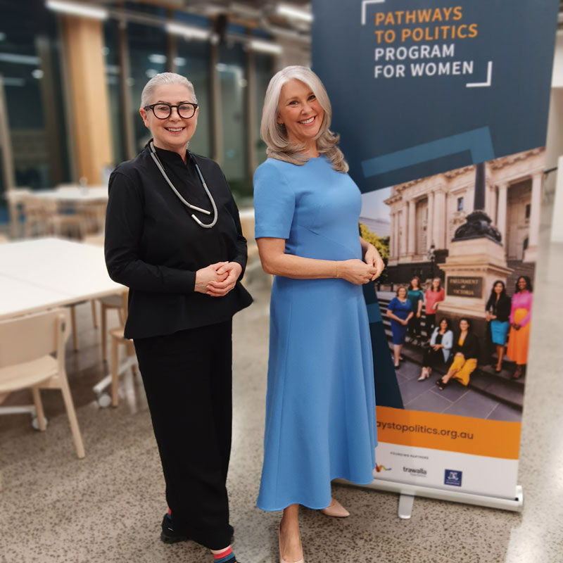 Dr Meredith Martin and Tracey Spicer pose in front of a Pathways to Politics banner