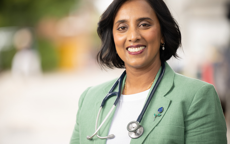Photo of Michelle Ananda-Rajah, a woman of south Asian appearance, wearing a green blazer and stethoscope around her neck