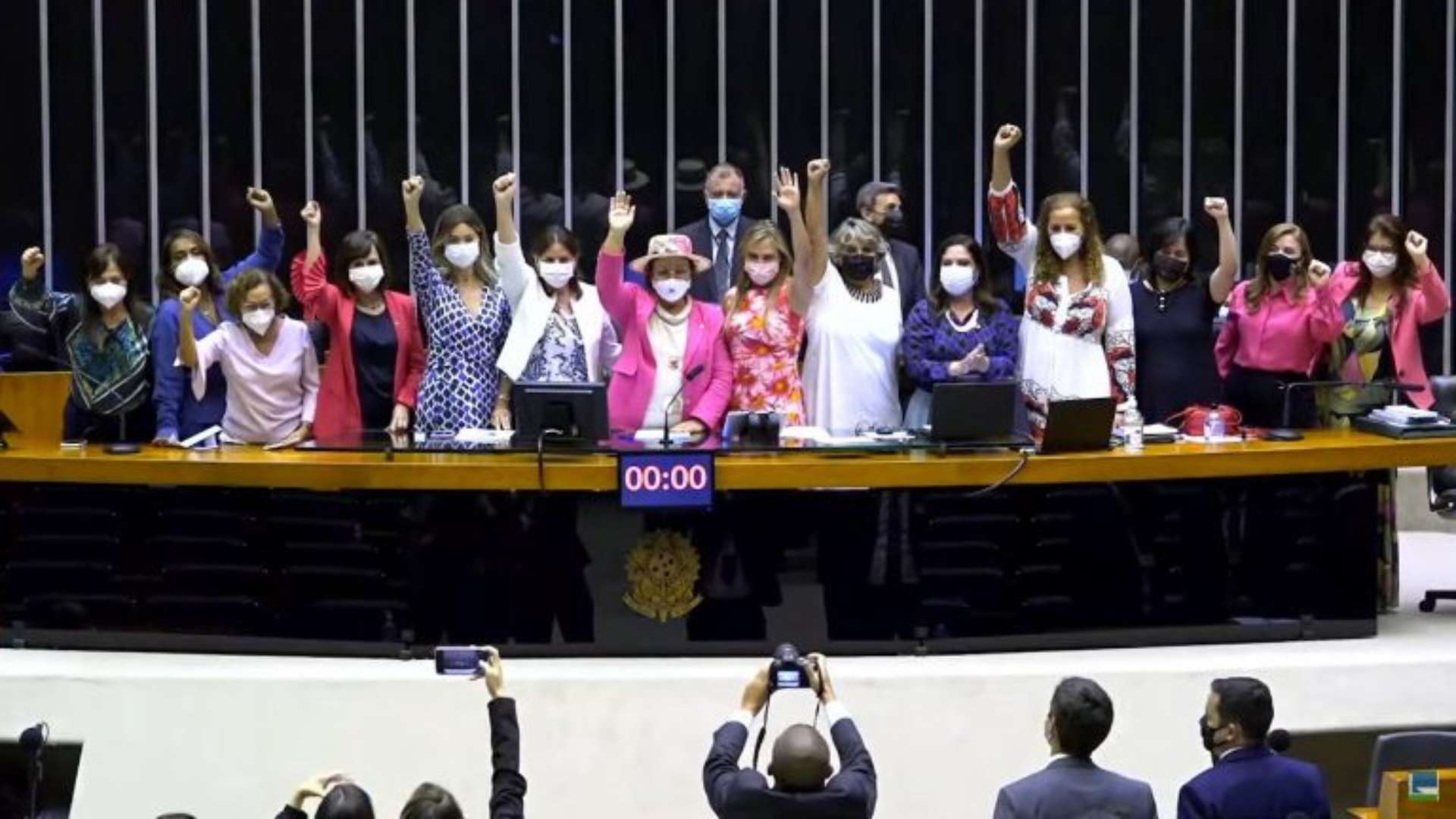Photo of women in Brazilian Parliament standing in a group with their right fists raised