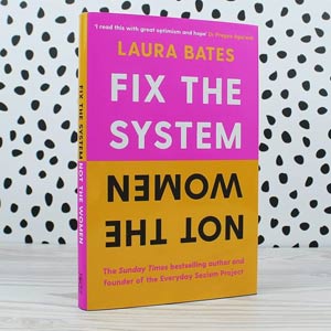 Photo of the book Fix the System Not the Women, hot pink and yellow, against a black and white spotted background