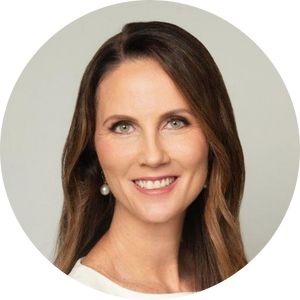 Photo of a smiling white woman with long, light brown hair, against a plain grey background