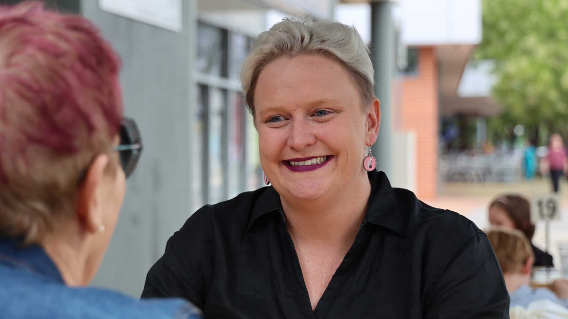 Photo of Heidi Prowse, a white woman with short bleached blond hair. She is smiling and wearing a black shirt.