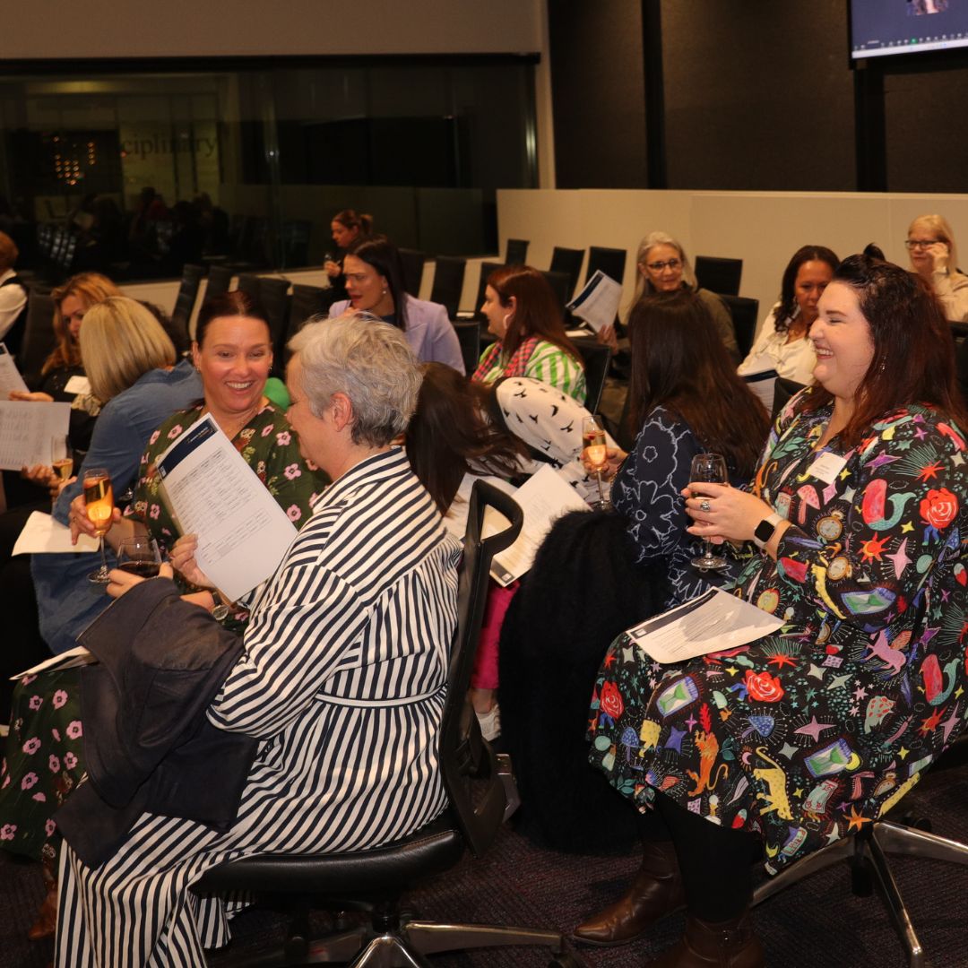 Photo of diverse women sitting in rows and holding papers