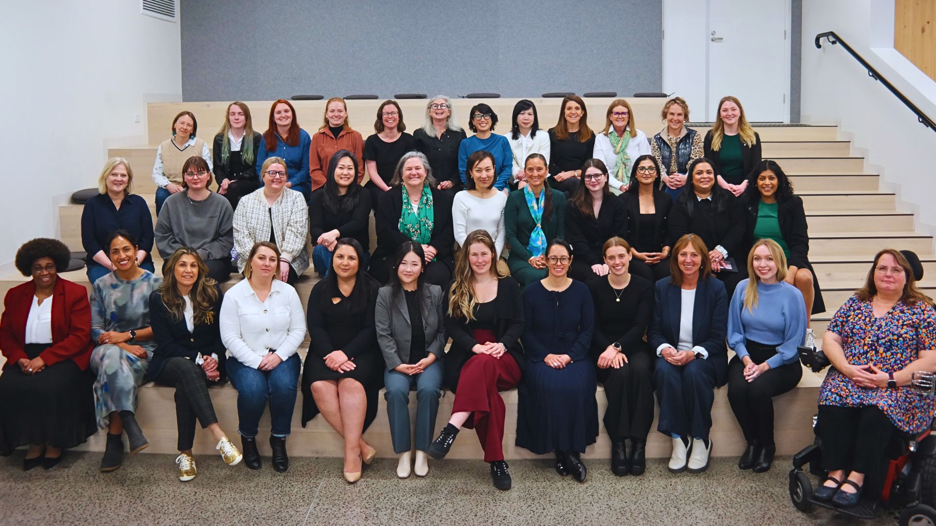 Large group of smiling diverse women posing for a photo grouped in three rows