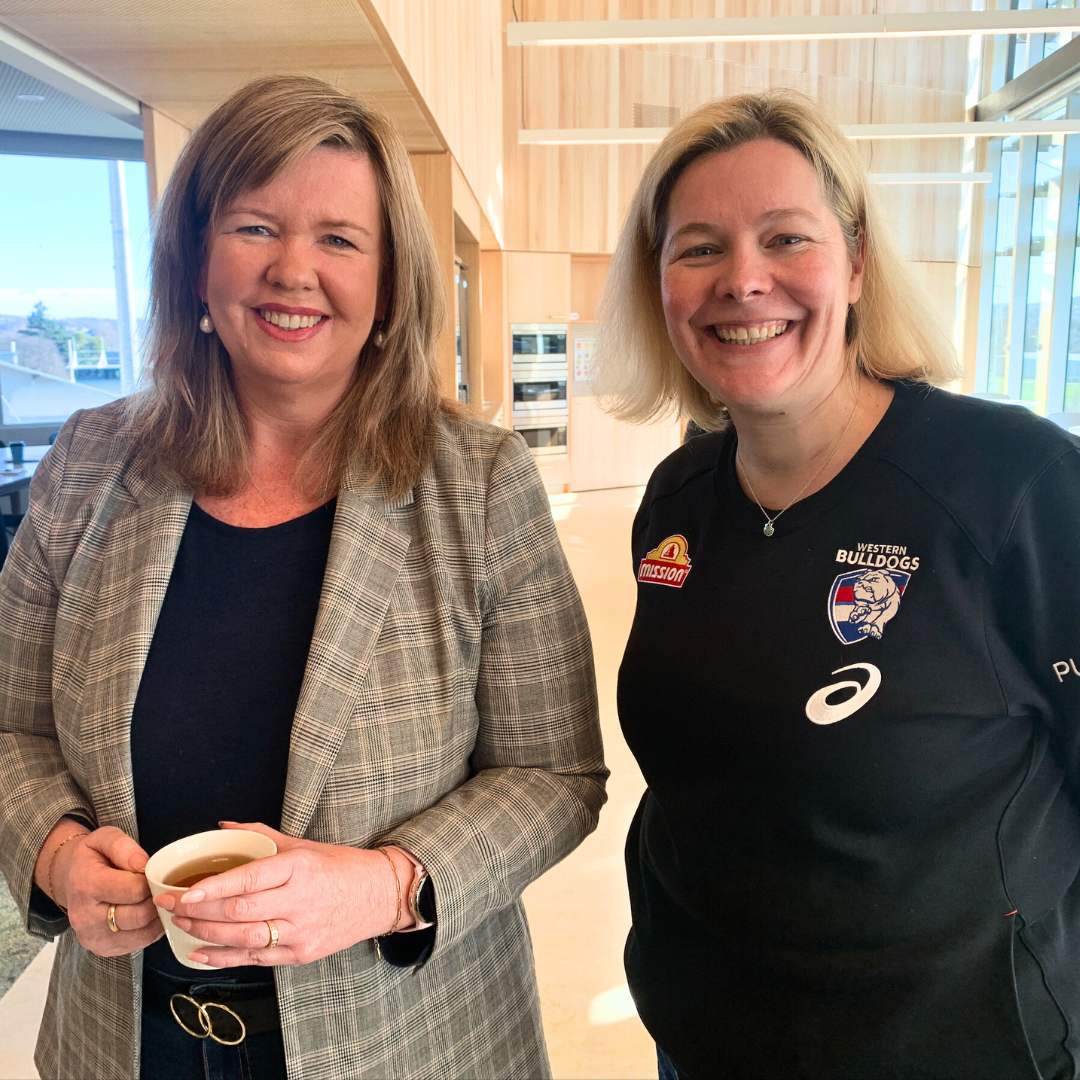 Photo of Bridget archer wearing a grey blazer, smiling next to another white woman wearing a black sporting jumper