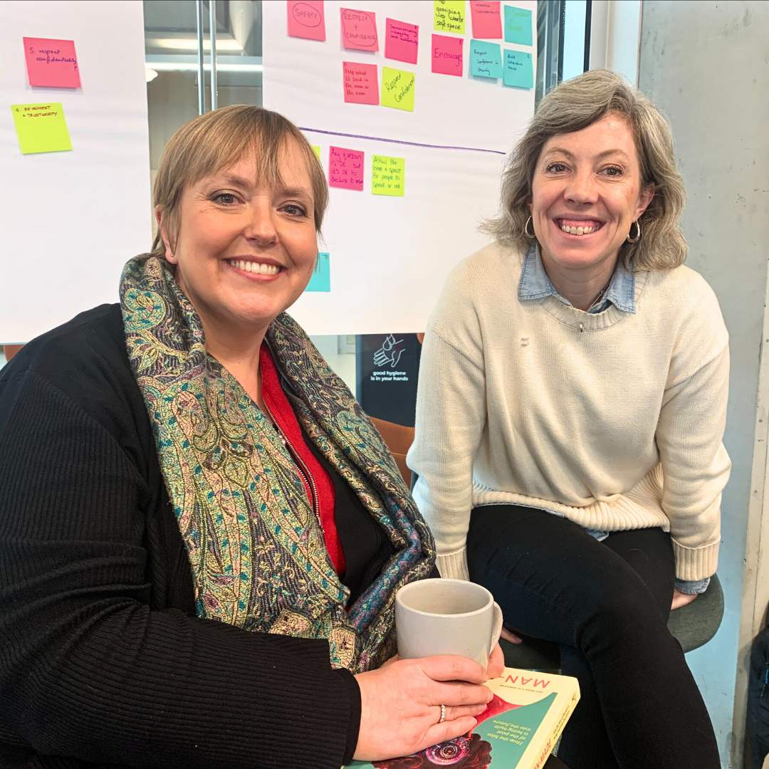 Photo of Lara Giddings and another woman smiling. A wall of post-it notes can be seen in the background.