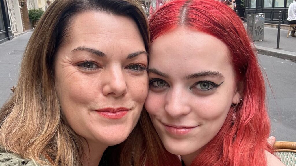 Photo of a woman and teenage girl, their faces pressed close together, smiling for a selfie