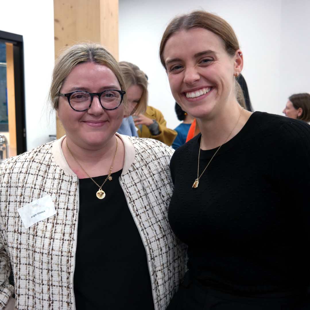 Two smiling women wearing black