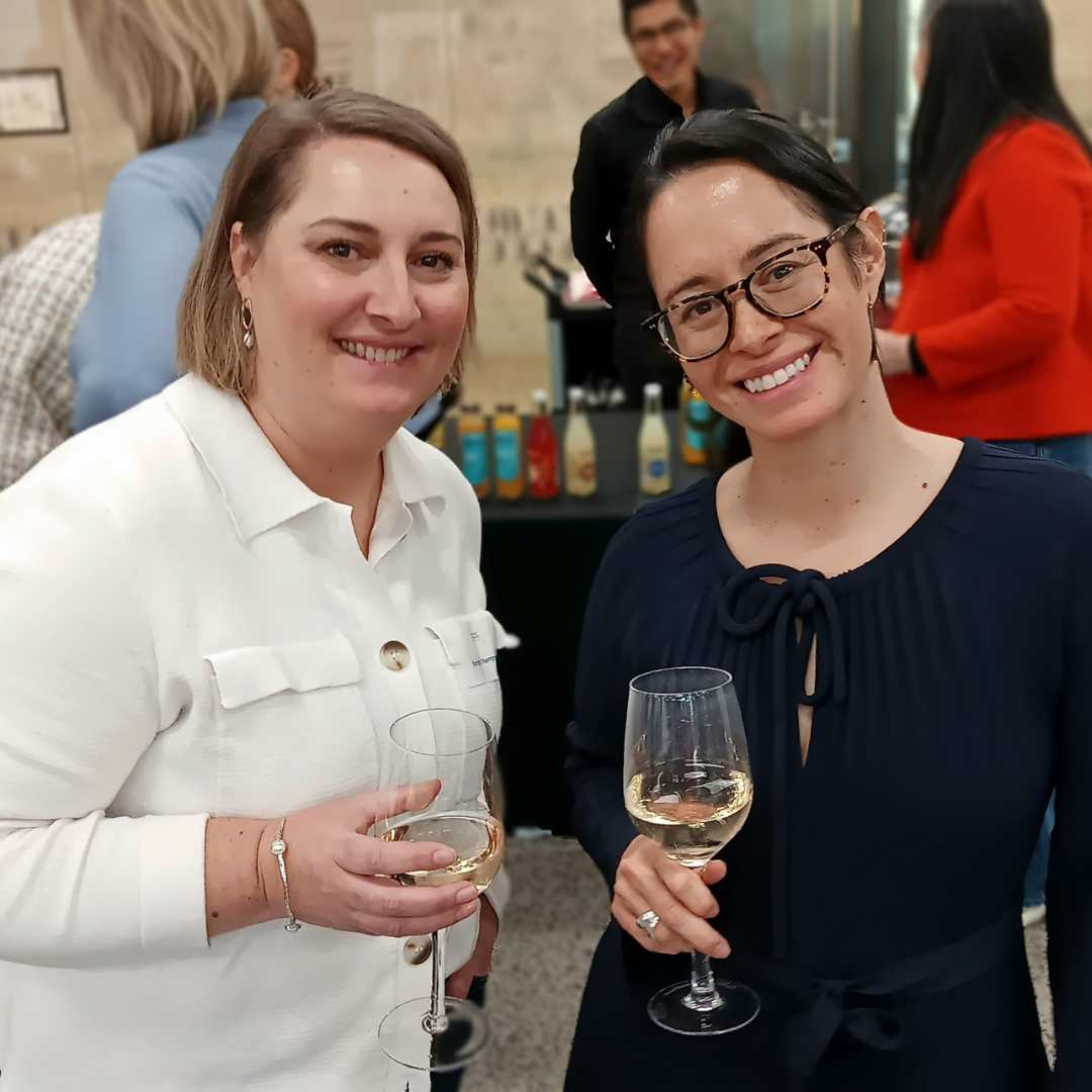 Two smiling women smiling and holding wine glasses