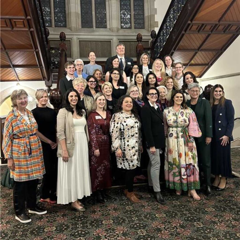 Large group of diverse women pose for a photo on a grand staircase