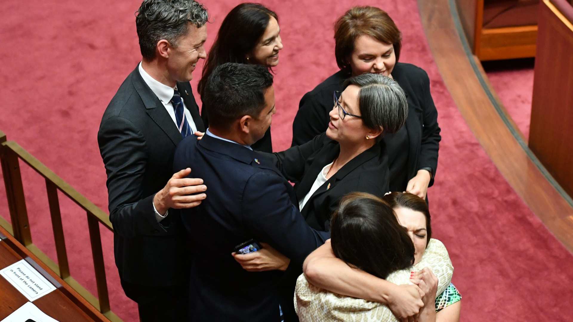 Mixed group of politicians in suits embracing in the senate chamber