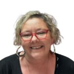 Photo of Leanne Shingles smiling, wearing red glasses and large hoop earrings