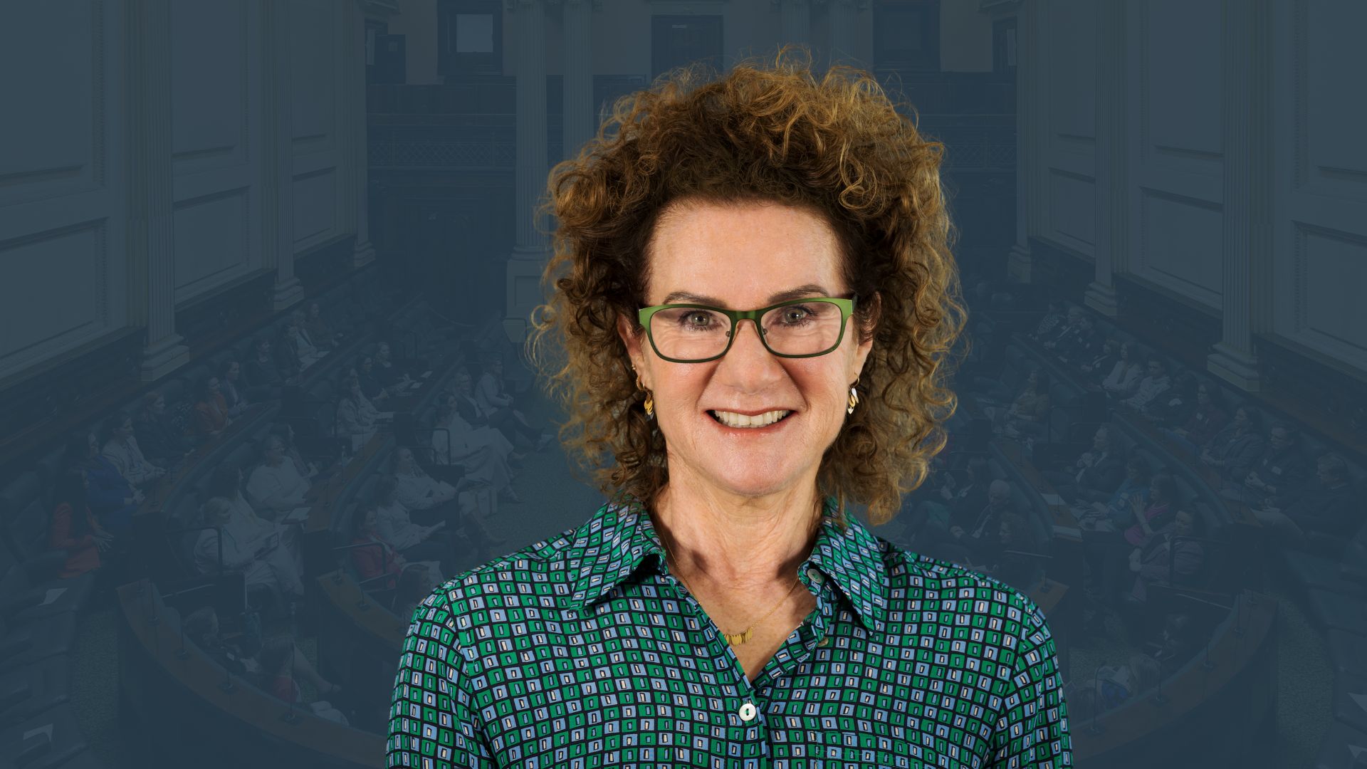 Photo of Carol Schwartz smiling, curly hair and glasses, against a dark blue/green background