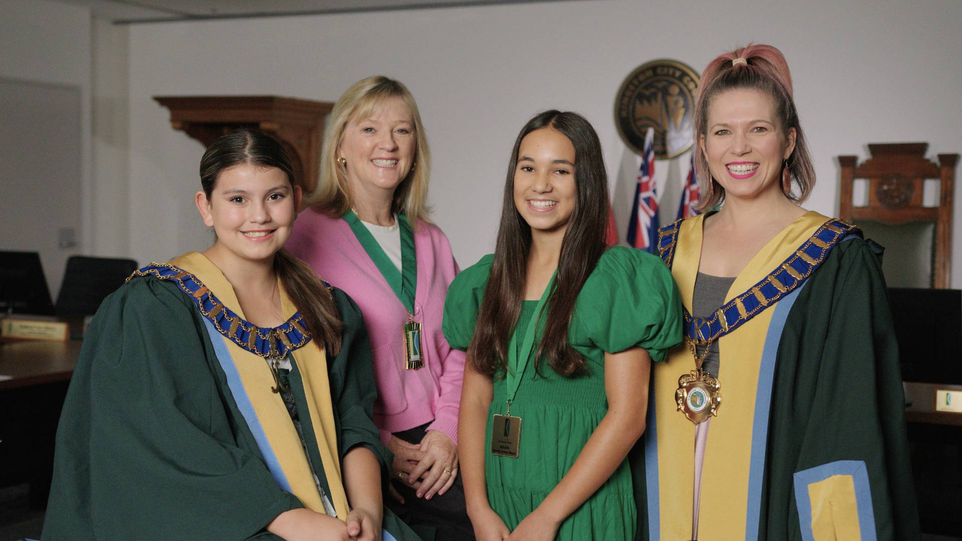 Two blonde women and two young teen girls smiling, dressed in mayoral robes