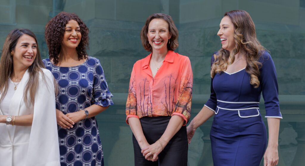 four smiling women in front of NSW Parliament