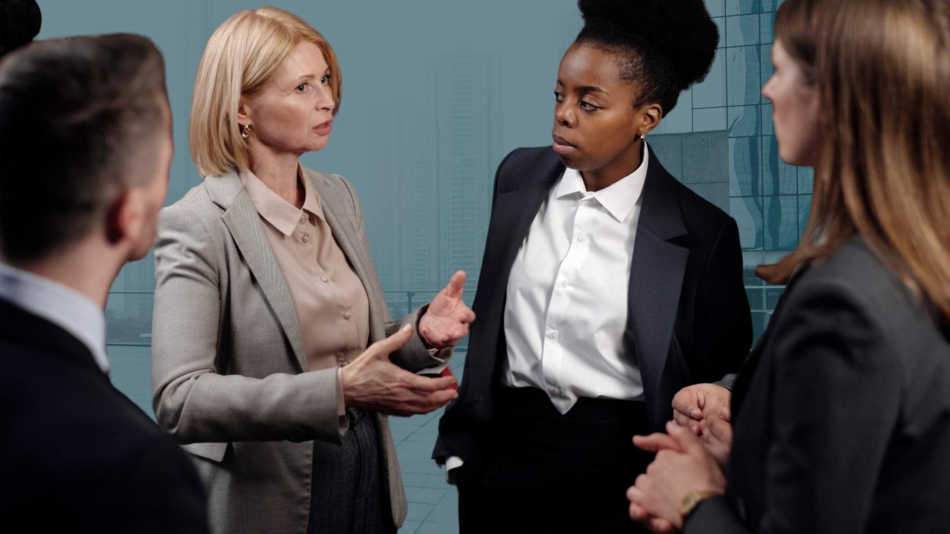 3 women and a man in business dress having a serious discussion