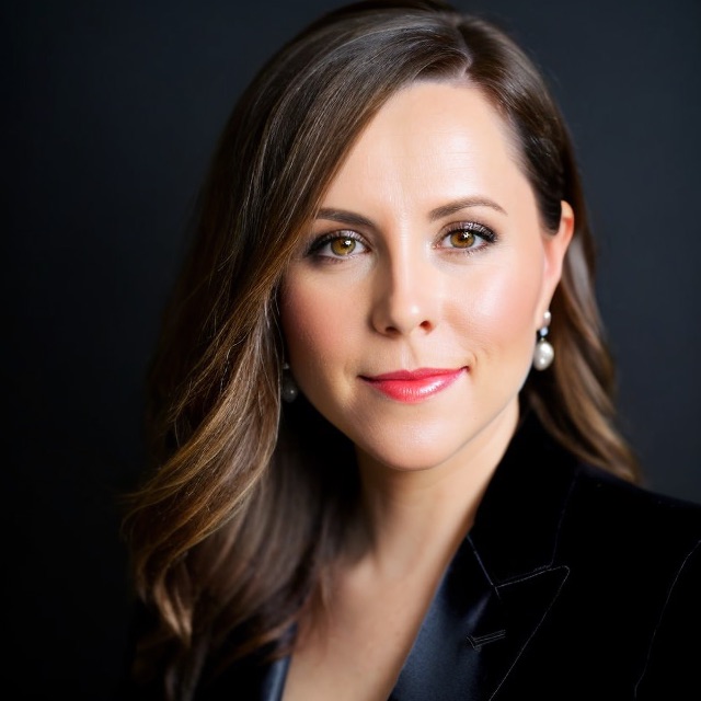 Photo of Hayley Van Loon, long brown hair, smiling, wearing black blazer